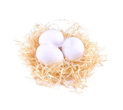 Three white eggs in the straw. White eggs in the nest isolated.
