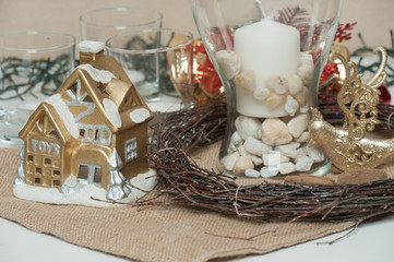 On the table are a candle, a small New Year's house. Christmas