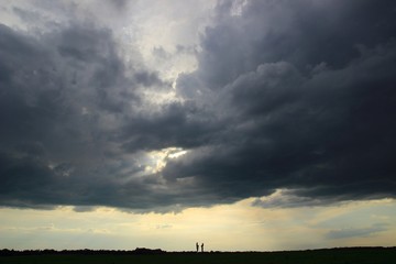 Obraz premium Silhouettes of two persons in conversation under storm cloud