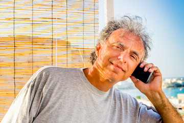 man talking on mobile phone in front of seaside panorama