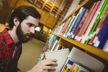 Happy student picking book in library