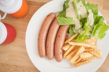 Three pieces of sausage with fresh vegetables, fried potatoes se