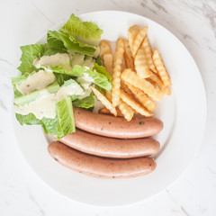 Three pieces of sausage with fresh vegetables, fried potatoes se