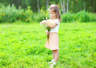 Naklejka na ściany i meble Cute smiling child with bouquet chamomiles flowers in summer day