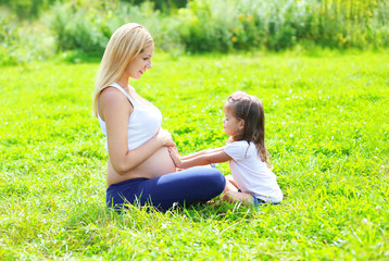 Happy pregnant woman, mother and little daughter child sitting o
