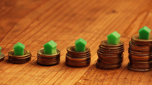 Home mortgage concept with small plastic house models on top of stacked coins