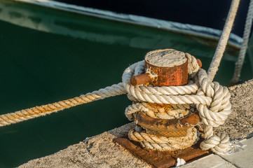 Ship rope tightly bound to the rusty quay.
