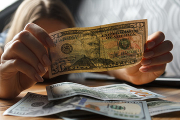Young happy woman count dollars on the table. 