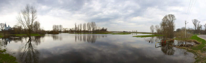 Spring flood with sky reflections and stormy weather. Panorama.