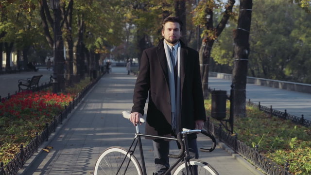 young businessman standing with bicycle and look in the camera