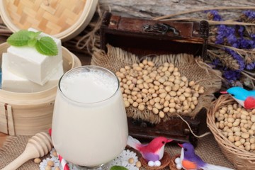 Soy milk and soybeans on wood background.