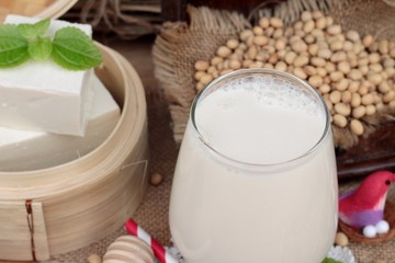 Soy milk and soybeans on wood background.