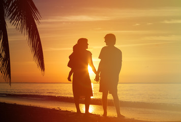 Fototapeta premium young couple with little child at sunset tropical beach