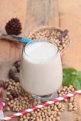 Soy milk and soybeans on wood background.