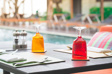 Red and Yellow Glass of water on luxury table setting near swimm