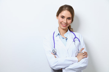 Friendly smiling young female doctor, standing near wall