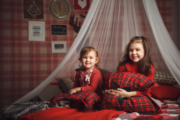 Two little cute girls on bed in scottish style