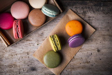 Tasty colorful macaroons in carton box on wooden background