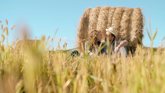 Young loving couple leaning on haystack and kissing