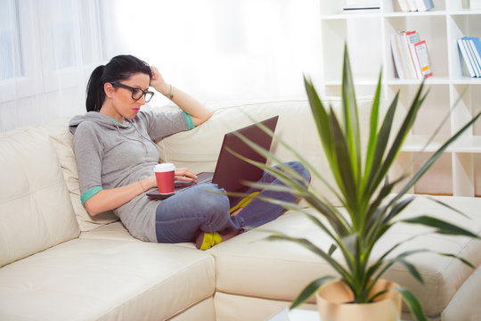 Woman using laptop sitting on sofa