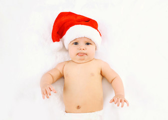 Christmas and family concept - cute funny baby in red santa hat