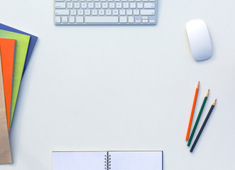 Creative Office White Table with Matching Color Orange Green Blue Magazines and Pencils Computer Keyboard and Mouse Opened Notepad Top View