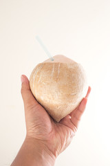 Hand holding fresh coconut ready to drink on white background