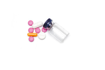 empty glass container from under pills. a variety of pills and capsules next to an empty glass flask from under medication isolated on white background