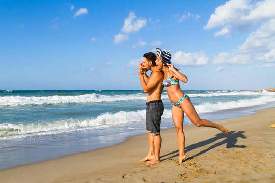Attractive young couple in bikini and shorts at the beach.