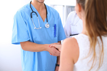 Male doctor and female patient shaking hands. Partnership, trust and medical ethics concept