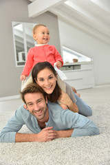 Obraz premium Parents and baby girl laying on carpet,