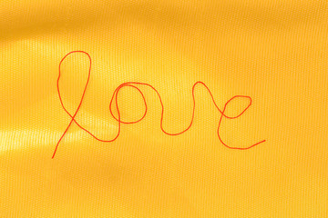 red thread - love sign - on textured silk background