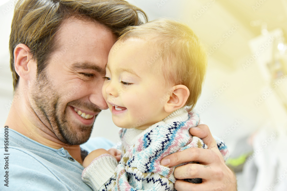 Wall mural Portrait of young man holding baby in arms