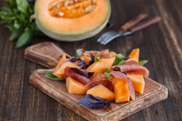 Appetizer, melon with jamon and Basil, on a wooden dosochka.selective focus