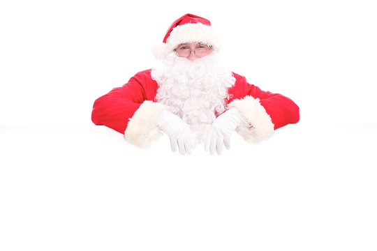 Kind Santa Claus looking out from behind the blank sign isolated on white background with copy space