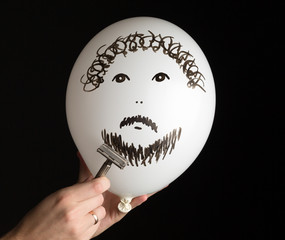 hand shaves a white ballon on a black background