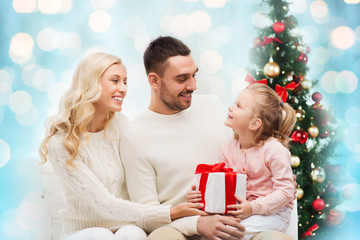 Fototapeta na wymiar happy family with gift box over christmas lights