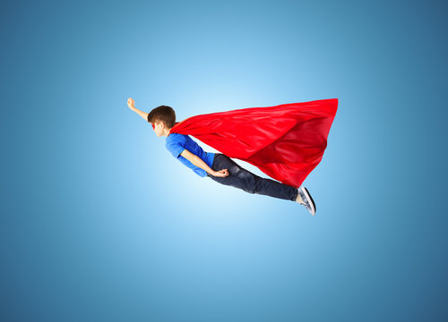 boy in red superhero cape and mask flying on air