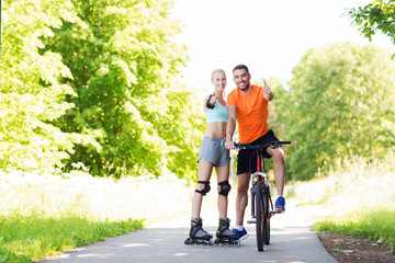 Fototapeta premium couple on rollerblades and bike showing thumbs up