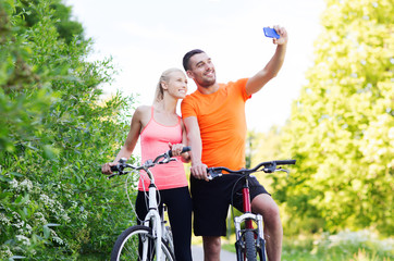 couple with bicycle taking selfie by smartphone
