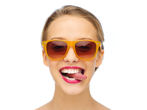 happy young woman in sunglasses showing tongue
