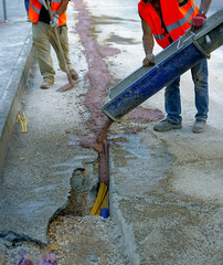fiber optic cables buried in a micro trench with concrete colored red by a worker