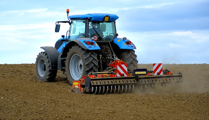 Obraz premium Agricultural Landscape - Tractor working on the field - summer sunny day
