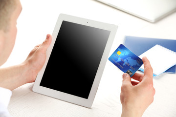 Man holding credit card and tablet on workplace background