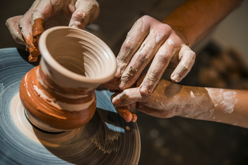 Master potter teaches the child how to make a pitcher on a pottery wheel - obrazy, fototapety, plakaty