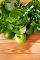 Green healthy juice with fruits and herbs on wooden table close up