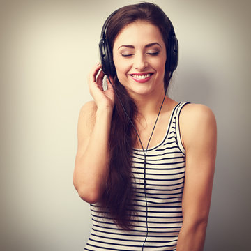 Laughing dj woman in headphones listening the music with closed