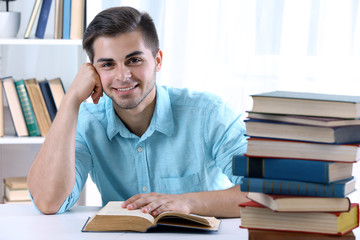 Young man reading book at table in room