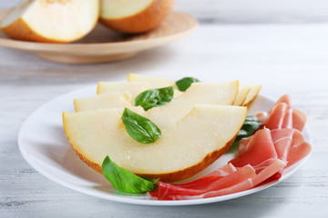 Melon with prosciutto of Parma ham on wooden table, closeup