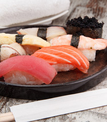 Sushi in a round plate over wooden background